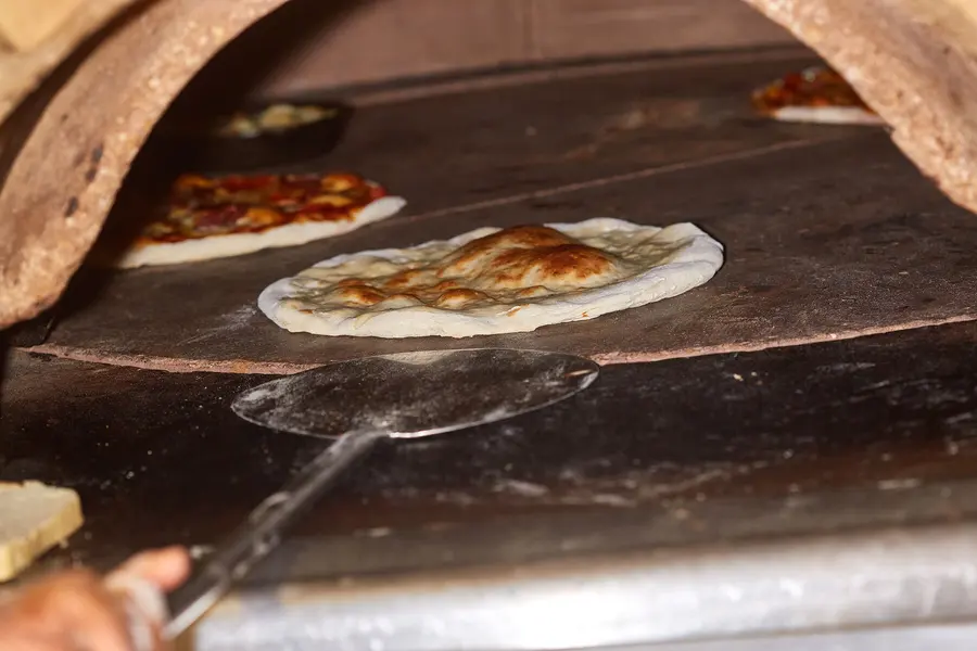 Pizza entrando al horno de piedra en la pala