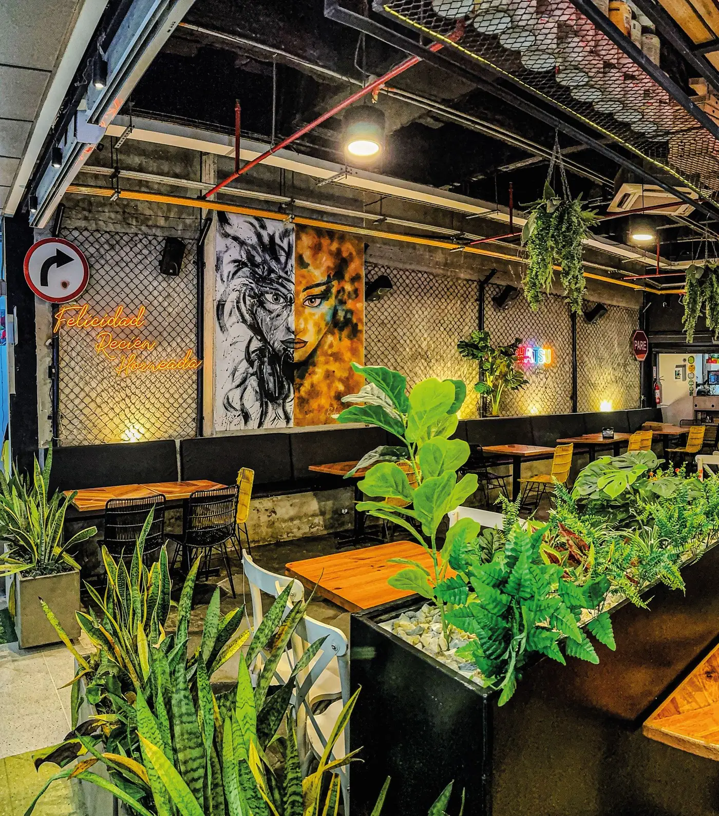 El salón de VIALETTO: mesas de madera, plantas y murales